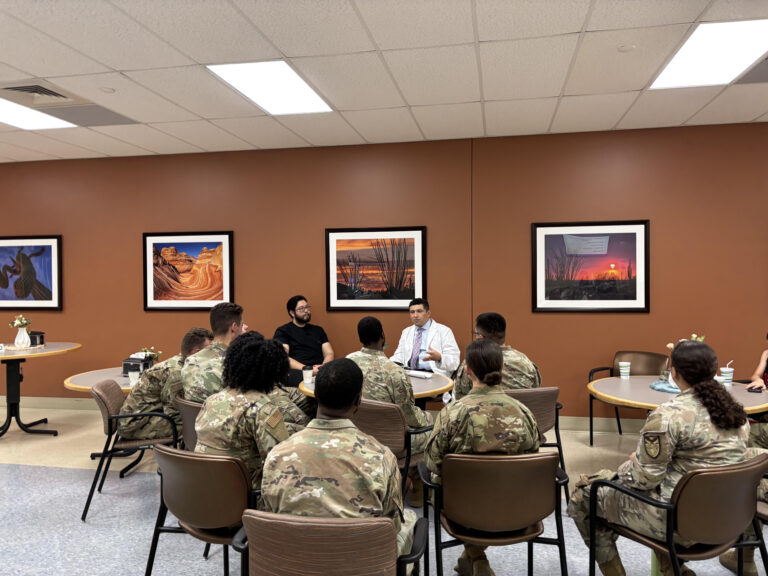 Dr. Kiyan Rad in a white coat leading a discussion with airmen from a Davis-Monthan Air Force Base leadership class at Encompass Health Rehabilitation Hospital of Northwest Tucson