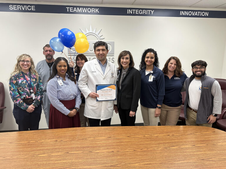 Dr. Kiyan Rad holding his Physician of the Month award for December 2023, surrounded by colleagues