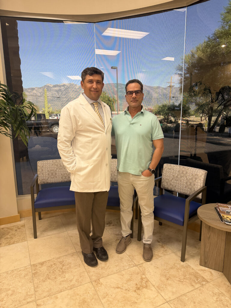 Dr. Kiyan Rad in a white coat with a visitor in the Sanova lobby, with the Santa Catalina Mountains in the window