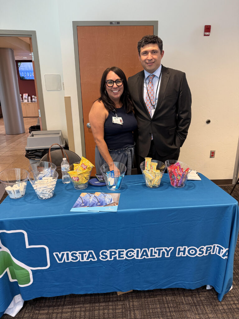 Dr. Kiyan Rad with a colleague at a Vista Specialty Hospital table during a Tucson community health event