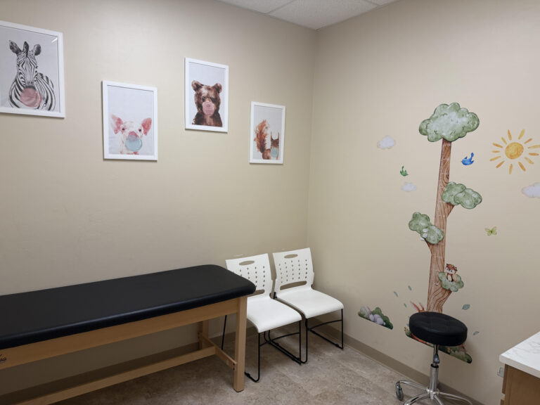 Kid-friendly pediatric exam room at Sanova Urgent Care with animal artwork and a tree growth chart on the wall