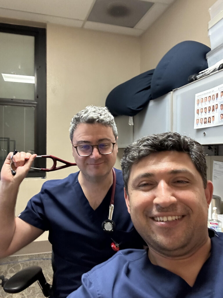 Dr. Kiyan Rad and a fellow physician in navy scrubs smiling at a workstation