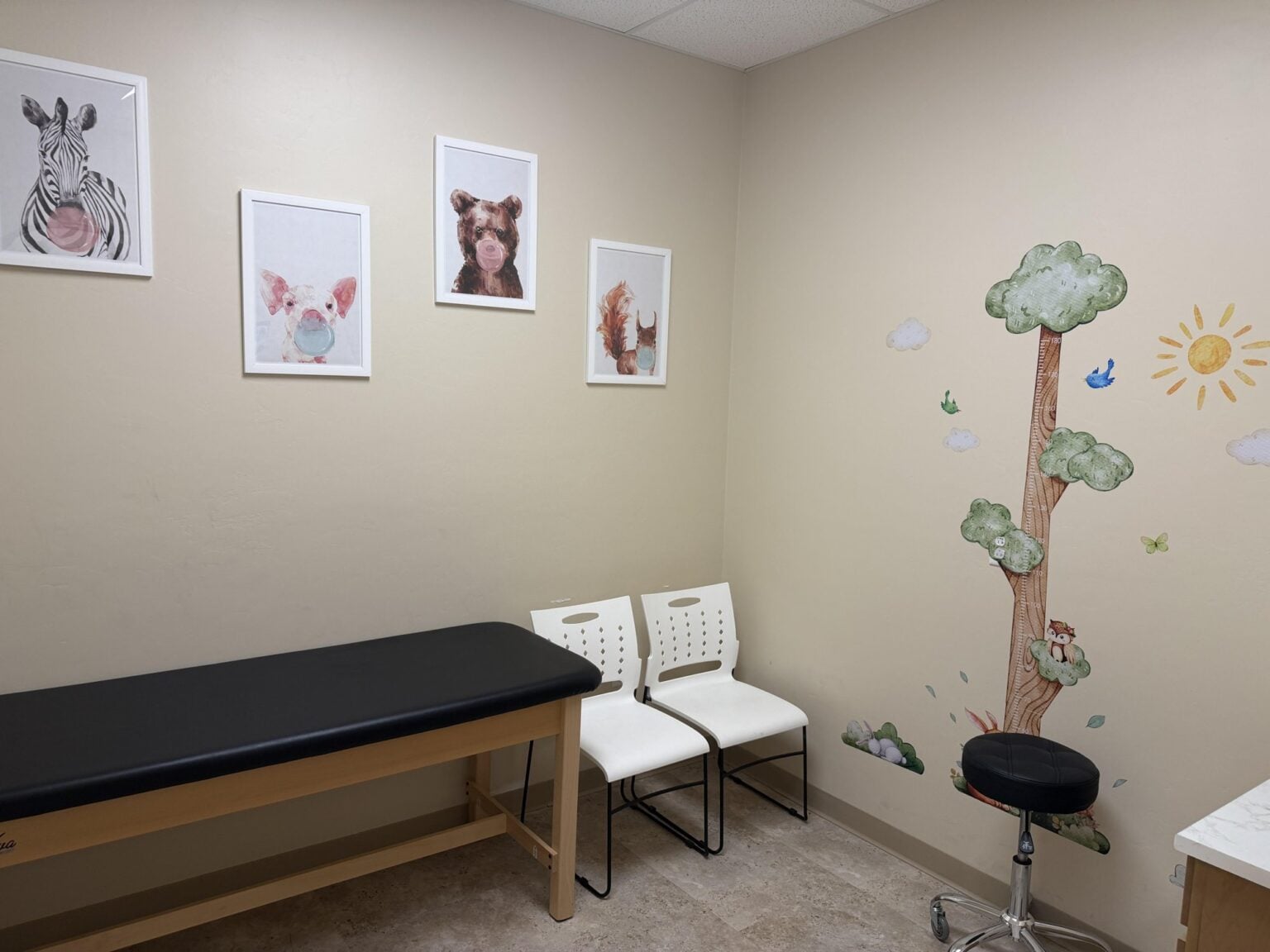 Kid-friendly pediatric exam room at Sanova Urgent Care with animal artwork and a tree growth chart, serving Oro Valley, Catalina and northwest Tucson families